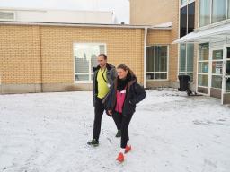 Mies ja nainen kävelevät Mynämäen kaupunginviraston edustalla talvisessa kelissä.